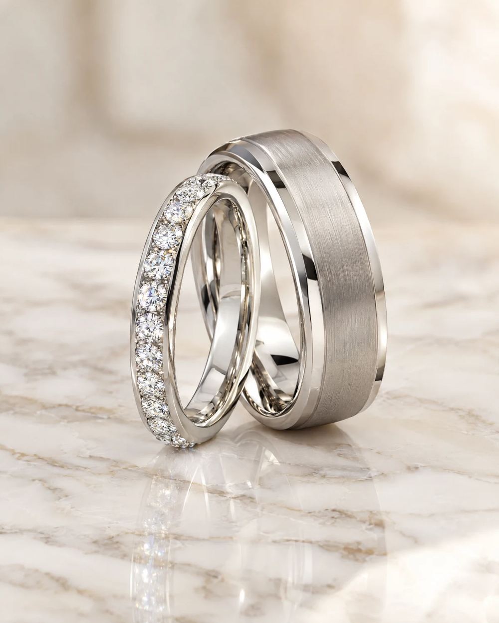 Matching platinum wedding bands, one set with diamonds, on white marble